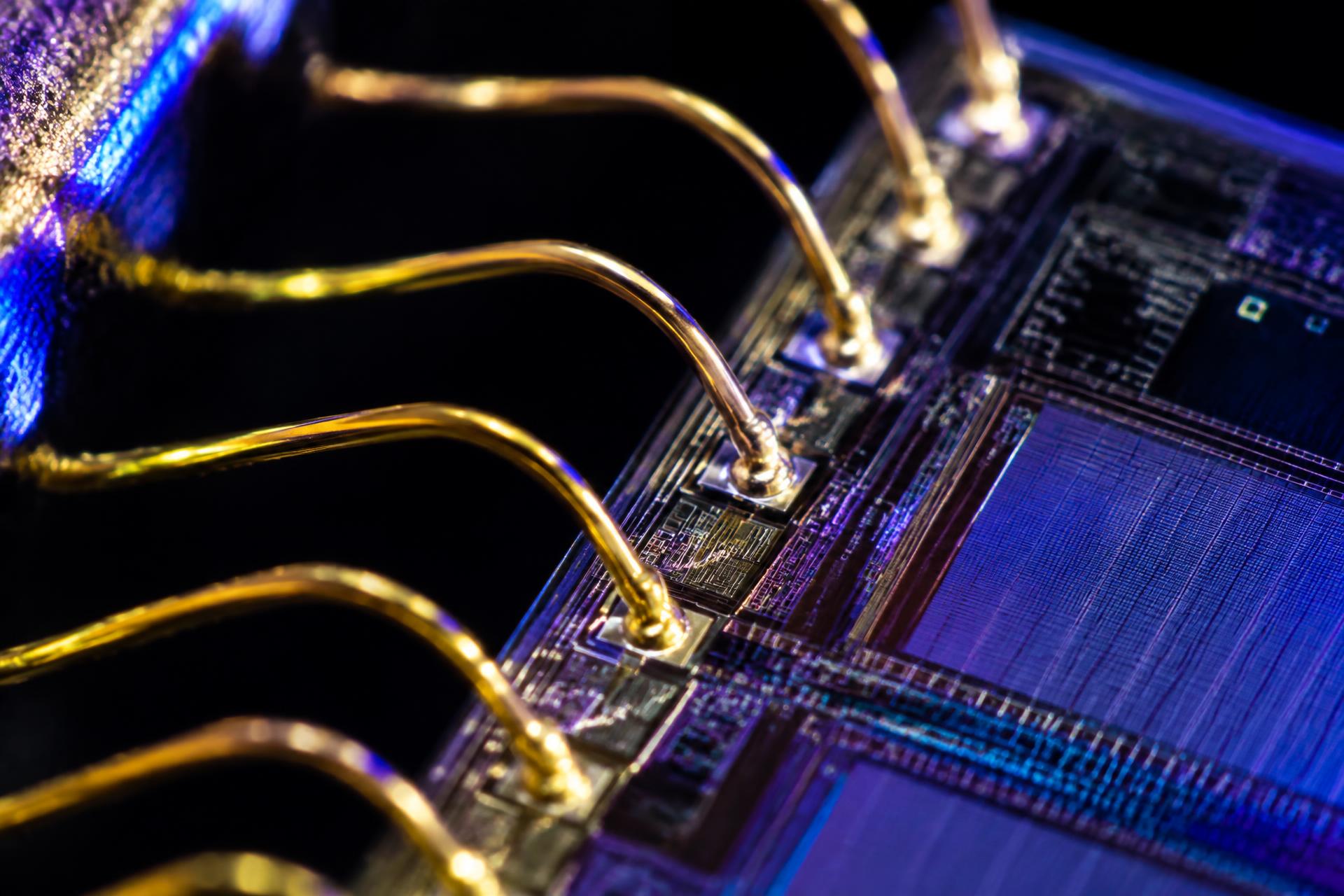Extreme close-up of gold wire bonds connecting to a semiconductor die